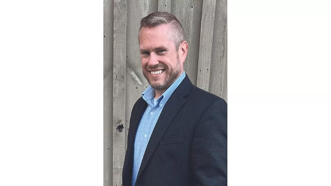 John Pimpo from Sokol posing in front of wood background smiling