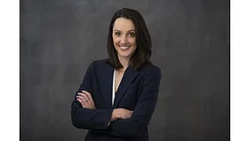 Lauren Davis of Skol posing in front of dark background with her arms crossed and smiling