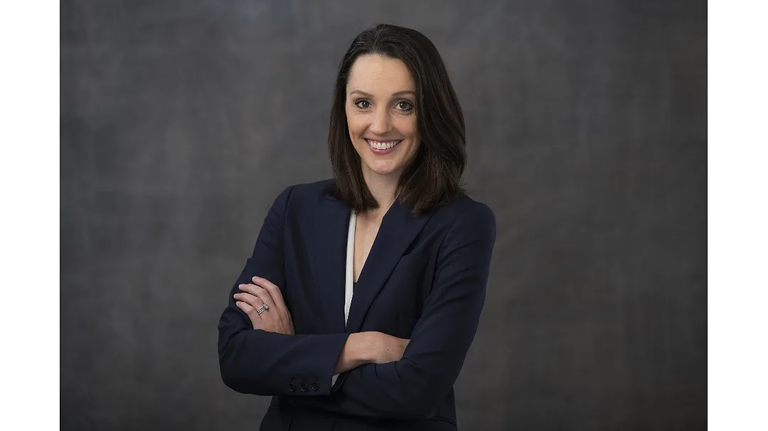 Lauren Davis of Sokol posing in front of a dark background with her arms crossed and smiling