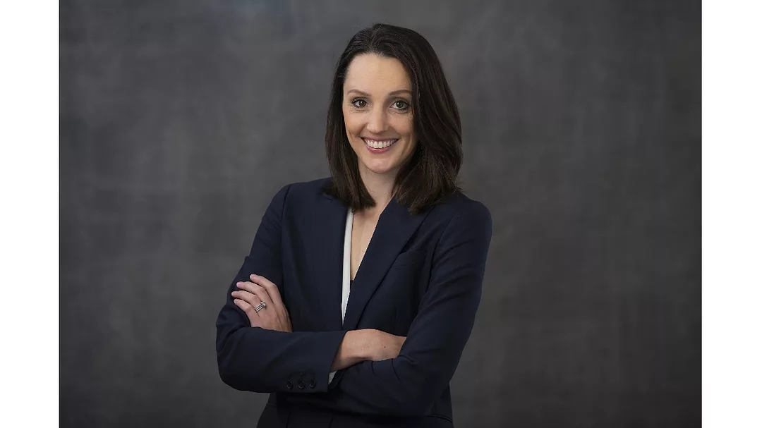 Lauren Davis of Sokol posing in front of a dark background with her arms crossed and smiling