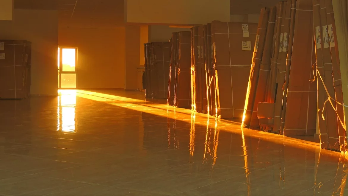 Image of large cardboard boxes lined up to the right of a room with a door open that is letting light leak through
