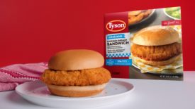 Tyson Food's frozen chicken sandwich on a plate, with its packaging behind it.