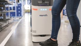 A person standing in from of a Rexroth brand autonomous mobile robot.