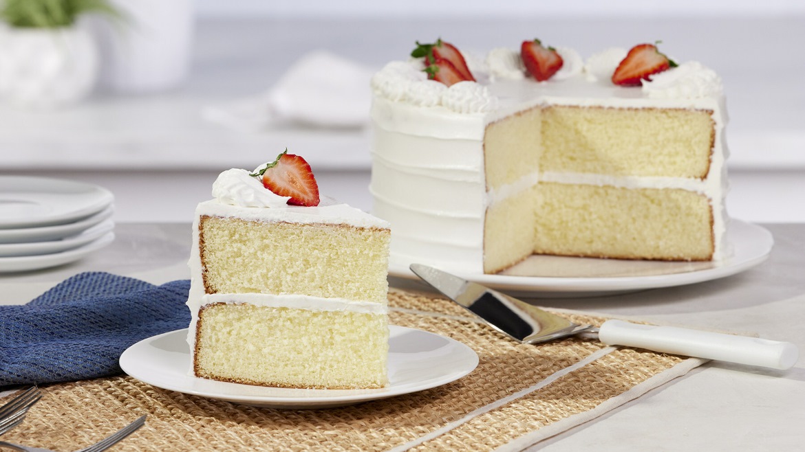 A white cake with white frosting and strawberries on top.