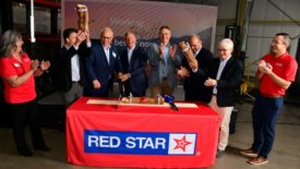 Red Star Yeast's ribbon cutting ceremony, with multple people behind a table with the Red Star Yeast logo