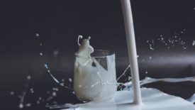Milk being poured into a small glass