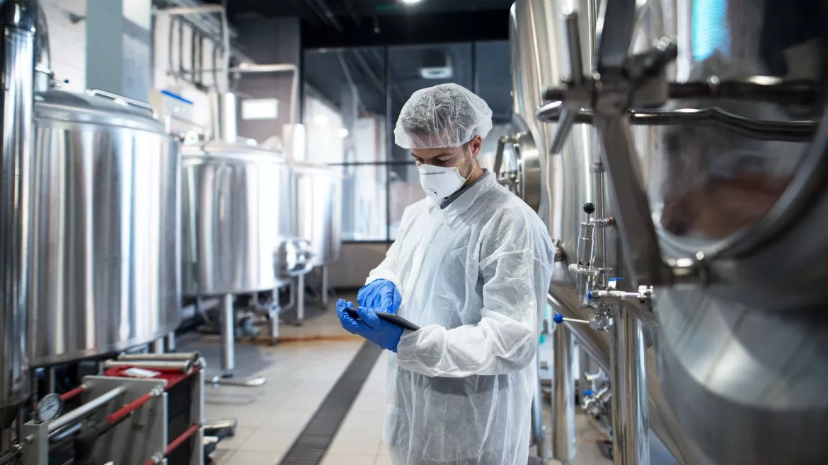 Man holding tablet near production tanks