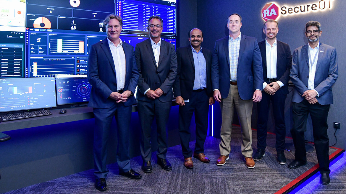 A group of men in suits posing in a room at the Rockwell Singapore Security Operations Center.