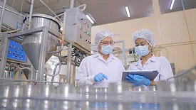 Quality assurance staff checking food moving along a conveyor belt in an automated production line.
