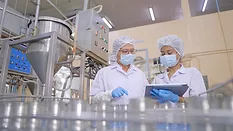 Quality assurance staff Quality assurance staff checking food moving along a conveyor belt in an automated production line.