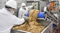 Food processing factory workers loading into a food cart.