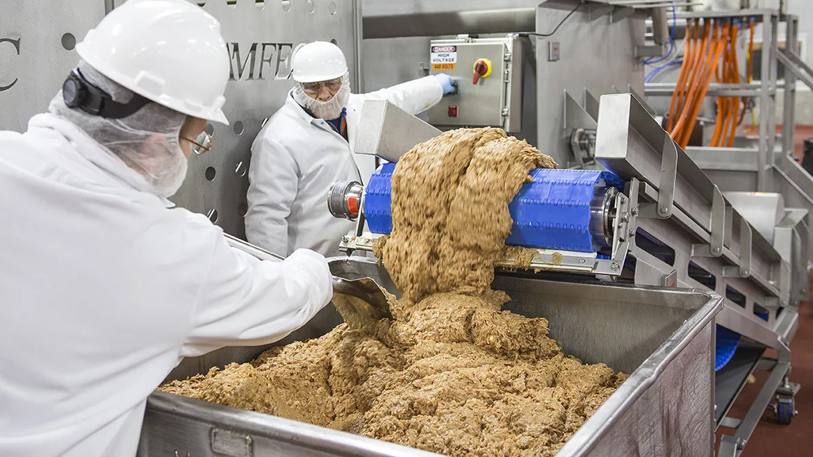 Food processing factory workers loading into a food cart.