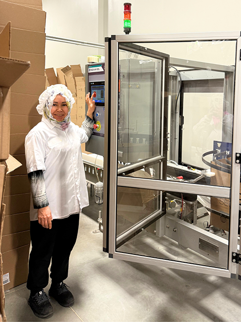 A Top Seedz employee standing next to equipment.