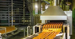 Bread going through conveyor belt in manufacturing plant.