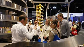 An event host is presenting to a group of PACK EXPO event attendees.