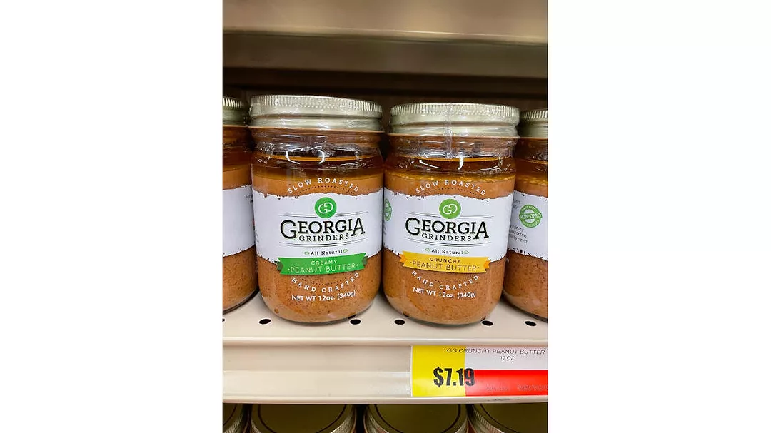 Two translucent jars of peanut butter labeled with “Georgia Grinder’s All Natural Peanut Butter.