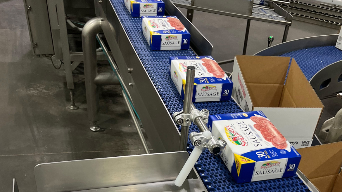 Packages of Swaggerty’s Farm, a family-owned premium sausage on a blue conveyor belt.